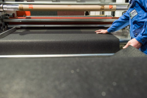 Eine Matte aus Gummigranulat wird mit Aluminiumfolie in den Werkhallen von PVP Triptis GmbH beschichtet. 